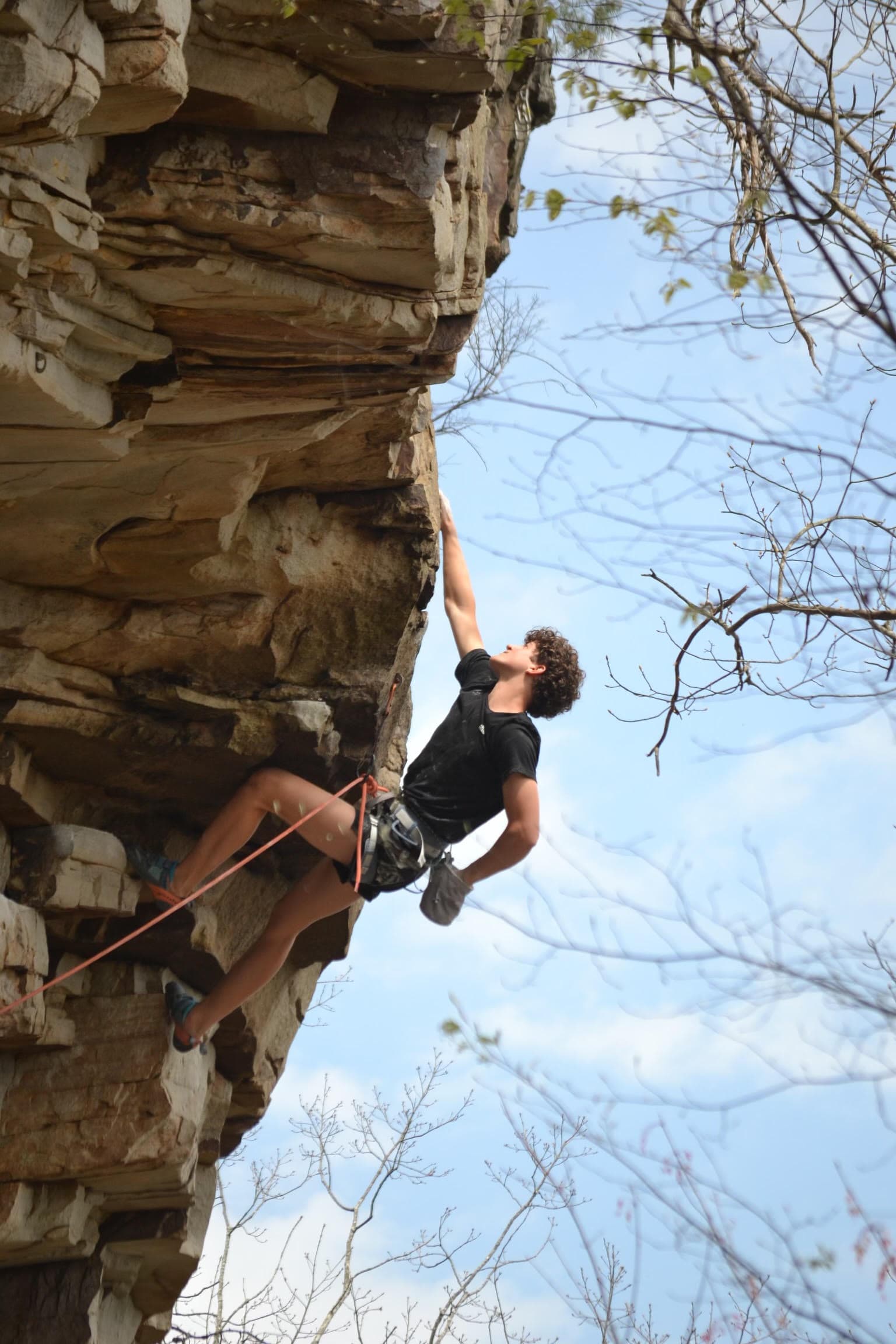 Spencer rock climbing outdoors, partway up a route